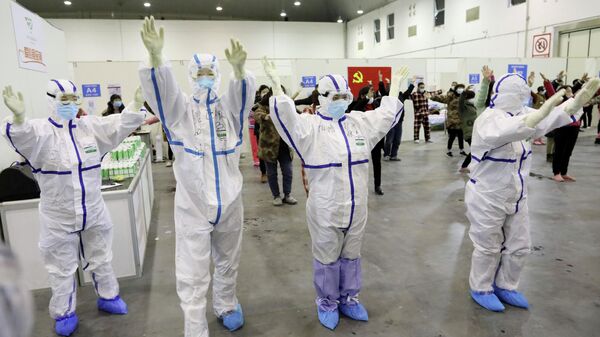 Медицинские работники в защитных костюмах танцуют с пациентами в конференц-центре города Ухань, который был преобразован в импровизированную больницу Медицинские работники в защитных костюмах танцуют с пациентами в конференц-центре города Ухань, который был преобразован в импровизированную больницу