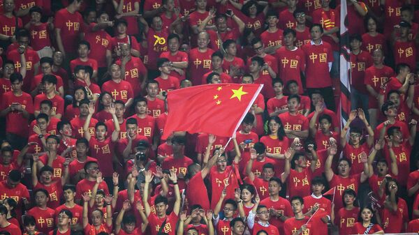 (FILES) This file photo taken on October 10, 2019 shows a fan waving the Chinese national flag as others cheer during the World Cup 2022 qualifier football match between China and Guam in Guangzhou. - The coronavirus exposes an ignorance of China's lucrative sports market and poor contingency planning, experts say, after Formula One became the most high-profile casualty of a mass pullout from the country. (Photo by STR / AFP) / - China OUT / TO GO WITH China-health-virus-sport,ANALYSIS by Peter STEBBINGS
