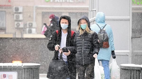 Молодые люди в медицинских масках на одной из улиц в Москве