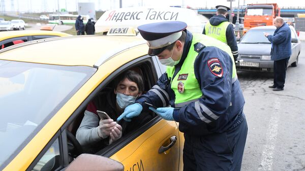 Сотрудник ДПС ГИБДД проверяет электронный пропуск у водителя такси при въезде в Москву Сотрудник ДПС ГИБДД проверяет электронный пропуск у водителя такси при въезде в Москву