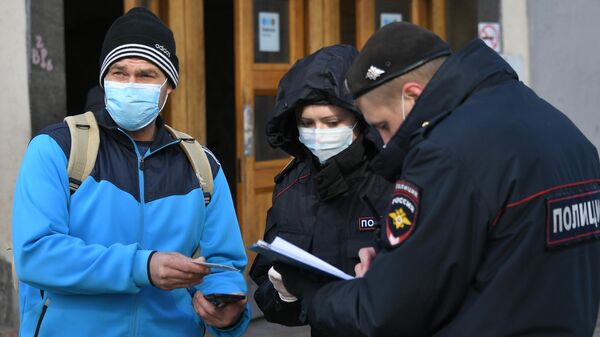 Сотрудники полиции проверяют цифровой пропуск у мужчины в Москве Сотрудники полиции проверяют цифровой пропуск у мужчины в Москве