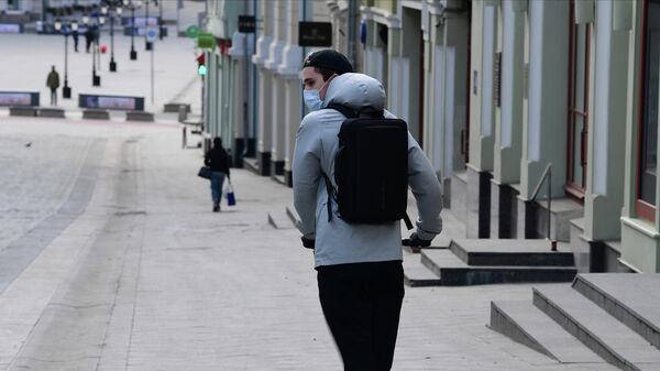 Молодой человек в защитной маске на самокате на улице Кузнецкий мост в Москве Молодой человек в защитной маске на самокате на улице Кузнецкий мост в Москве