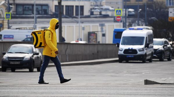 Курьер службы доставки Яндекс. Еда в защитной маске на одной из улиц Москвы