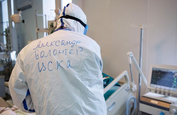 Волонтер возле кровати пациента в отделении реанимации и интенсивной терапии госпиталя COVID-19 в ГКБ No1 имени Н.И. Пирогова в Москве Волонтер возле кровати пациента в отделении реанимации и интенсивной терапии госпиталя COVID-19 в ГКБ No1 имени Н.И. Пирогова в Москве