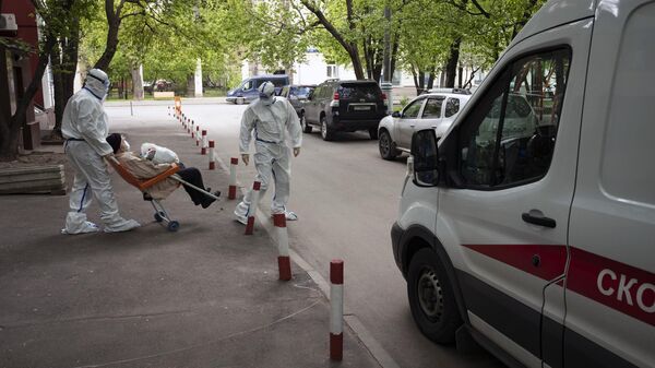 Медики бригады скорой помощи транспортируют пожилого мужчину в автомобиль Медики бригады скорой помощи транспортируют пожилого мужчину в автомобиль