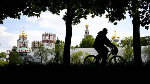 Мужчина катается на велосипеде в сквере у Новодевичьего женского монастыря в Москве Мужчина катается на велосипеде в сквере у Новодевичьего женского монастыря в Москве