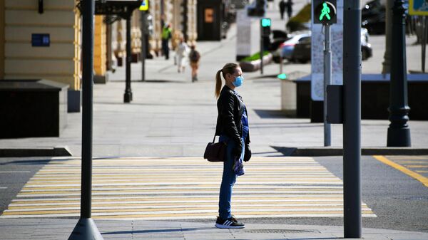 Девушка в медицинской маске и перчатках на одной из улиц в Москве Девушка в медицинской маске и перчатках на одной из улиц в Москве