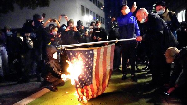 Протестующие в Портленде поджигают американский флаг Протестующие в Портленде поджигают американский флаг