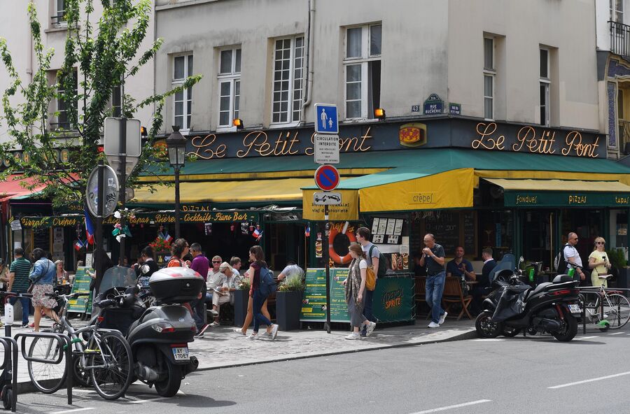 Горожане и туристы на улице Rue du Petit Pont рядом с пабом Cafe Le Petit Pont в Париже Горожане и туристы на улице Rue du Petit Pont рядом с пабом Cafe Le Petit Pont в Париже