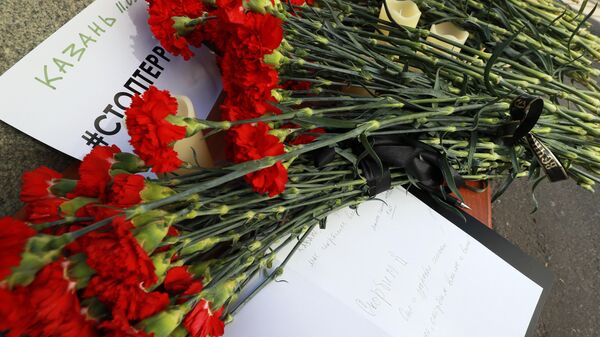 Люди несут цветы к казанской гимназии
