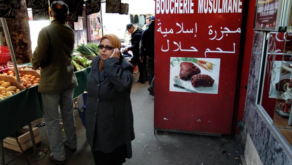 Покупательница проходит мимо мясной лавки с халяльными продуктами для мусульман на рынке в Париже Покупательница проходит мимо мясной лавки с халяльными продуктами для мусульман на рынке в Париже