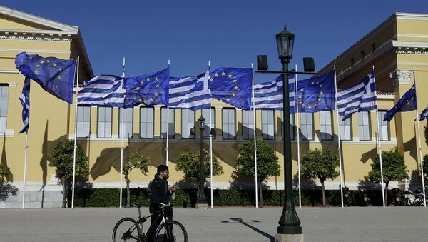 Мужчина с велосипедом на фоне флагов Греции и Евросоюза. Архивное фото Мужчина с велосипедом на фоне флагов Греции и Евросоюза. Архивное фото