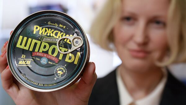 Девушка демонстрирует рыбные консервы Рижские шпроты. Архивное фото Девушка демонстрирует рыбные консервы Рижские шпроты. Архивное фото