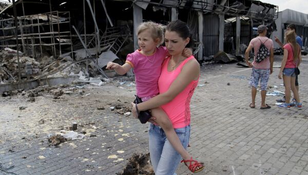 Женщина с ребенком проходит мимо рынка, разрушенного в результате обстрелов, в Донецке Женщина с ребенком проходит мимо рынка, разрушенного в результате обстрелов, в Донецке