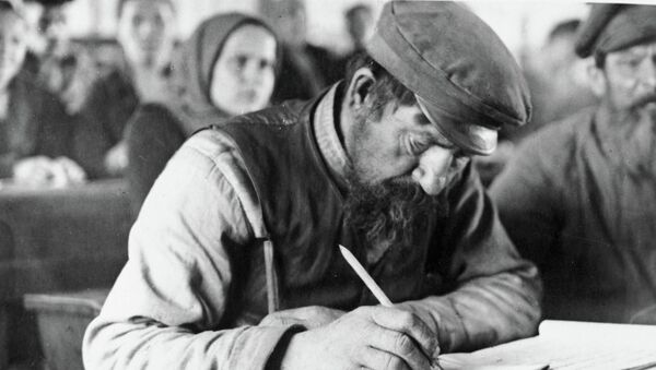 Пожилой мужчина выводит первые буквы на занятиях кружка ликбеза Пожилой мужчина выводит первые буквы на занятиях кружка ликбеза