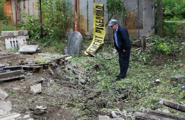 Мужчина рассматривает воронку от разорвавшегося снаряда в результате обстрела Донецка Мужчина рассматривает воронку от разорвавшегося снаряда в результате обстрела Донецка