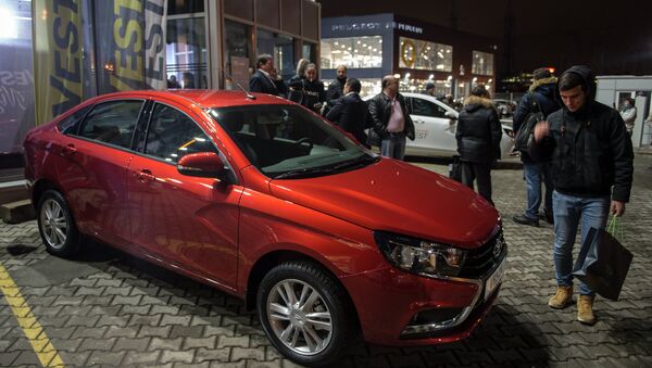 Молодые люди осматривают автомобиль Lada Vesta после начала продаж в Москве Молодые люди осматривают автомобиль Lada Vesta после начала продаж в Москве