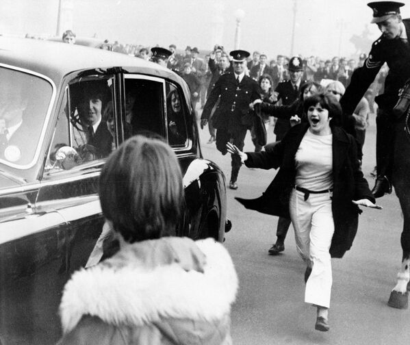 Автомобиль с участниками группы The Beatles в окружении фанатов. Лондон, Англия. 1965 год Автомобиль с участниками группы The Beatles в окружении фанатов. Лондон, Англия. 1965 год