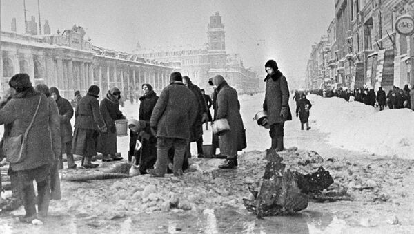 Жители блокадного Ленинграда набирают воду, появившуюся после артобстрела в пробоинах в асфальте Жители блокадного Ленинграда набирают воду, появившуюся после артобстрела в пробоинах в асфальте