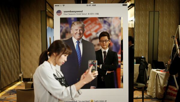 Девушка фотографирует своего друга на фоне портрета кандидата в президенты США Дональда Трампа в отеле в Сеуле Девушка фотографирует своего друга на фоне портрета кандидата в президенты США Дональда Трампа в отеле в Сеуле