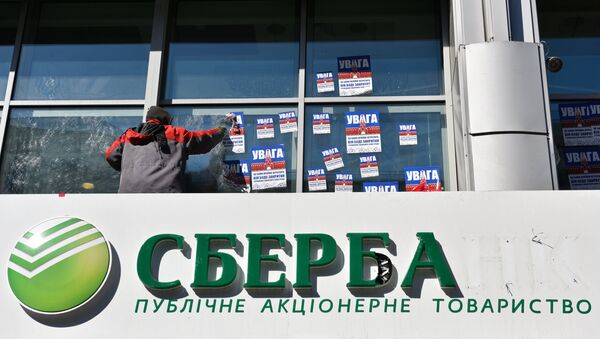 Рабочий очищает фасад центрального отделения дочернего предприятия Сбербанка России в Киеве от листовок Рабочий очищает фасад центрального отделения дочернего предприятия Сбербанка России в Киеве от листовок