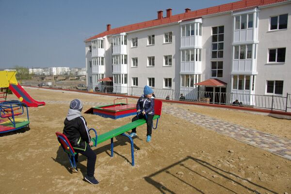 Дети играют на детской площадке у новых домов в Крыму, построенных для переселенцев из зоны строительства Керченского моста Дети играют на детской площадке у новых домов в Крыму, построенных для переселенцев из зоны строительства Керченского моста