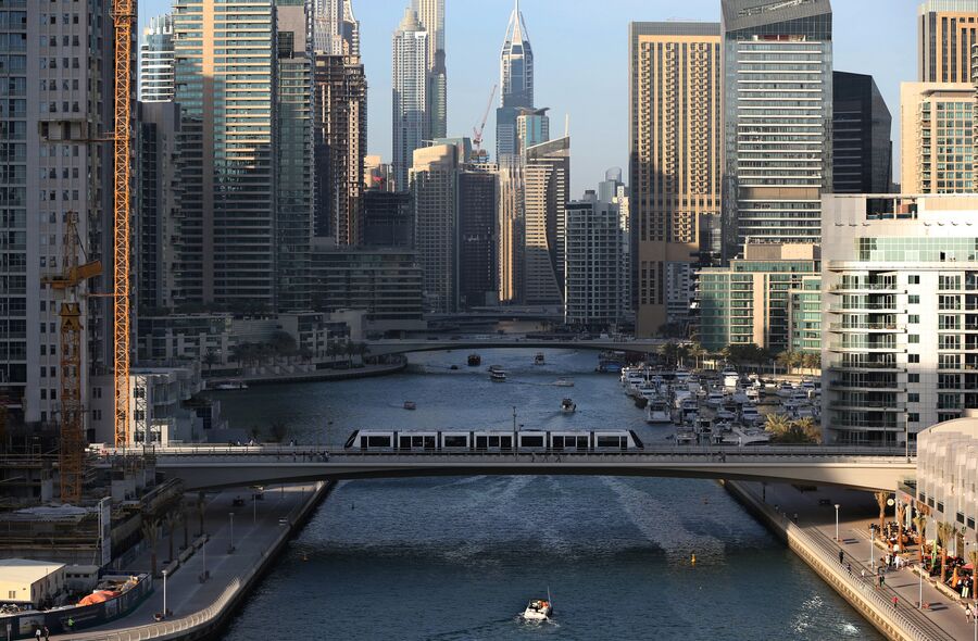 Трамвай проезжает по мосту через канал в Дубае 