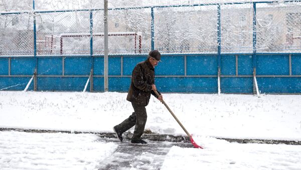 Мужчина убирает снег во дворе жилого дома. Архивное фото Мужчина убирает снег во дворе жилого дома. Архивное фото