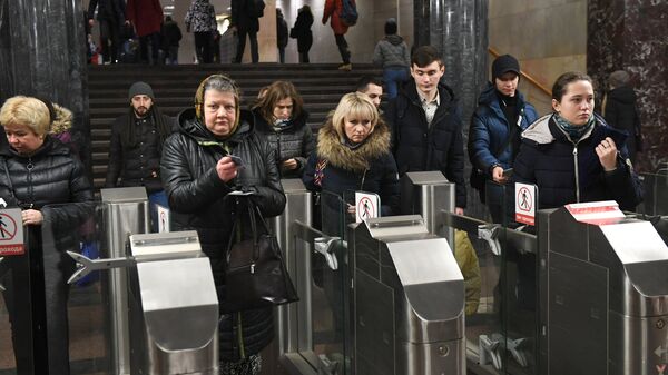 Пассажиры проходят через турникеты в московском метрополитене Пассажиры проходят через турникеты в московском метрополитене