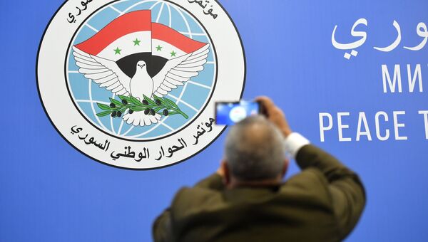 Мужчина фотографирует эмблему конгресса сирийского национального диалога в Сочи Мужчина фотографирует эмблему конгресса сирийского национального диалога в Сочи