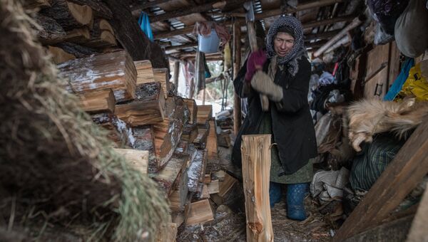 Агафья Карповна колет дрова.