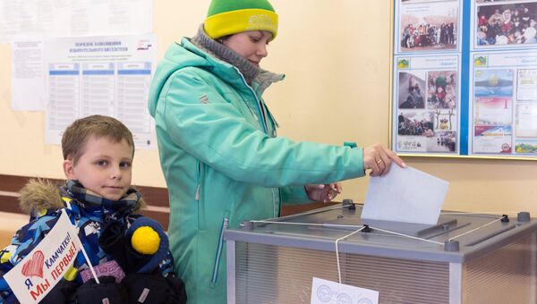 Женщина опускает бюллетень в урну на выборах президента РФ на избирательном участке №51 в Петропавловске-Камчатском. Женщина опускает бюллетень в урну на выборах президента РФ на избирательном участке №51 в Петропавловске-Камчатском.