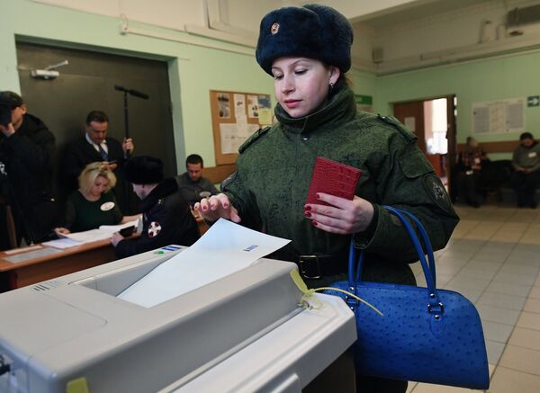 Женщина опускает бюллетень в урну на выборах президента РФ на избирательном участке №76 в Москве. 18 марта 2018 Женщина опускает бюллетень в урну на выборах президента РФ на избирательном участке №76 в Москве. 18 марта 2018
