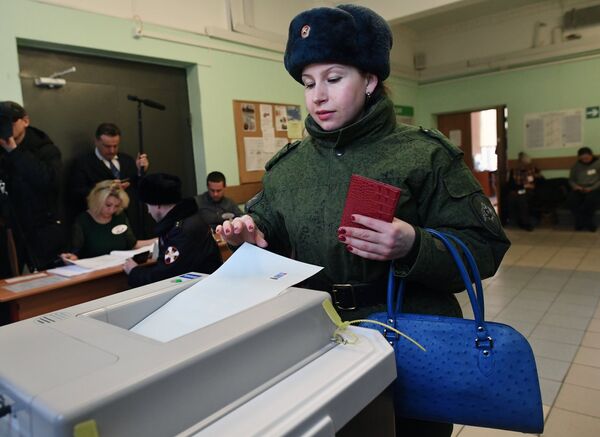 Женщина опускает бюллетень в урну на выборах президента РФ на избирательном участке №76 в Москве. 18 марта 2018 Женщина опускает бюллетень в урну на выборах президента РФ на избирательном участке №76 в Москве. 18 марта 2018