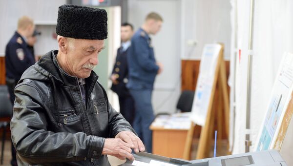 Мужчина опускает бюллетень в урну во время голосования на выборах президента Российской Федерации на избирательном участке в Симферополе.18 марта 2018 Мужчина опускает бюллетень в урну во время голосования на выборах президента Российской Федерации на избирательном участке в Симферополе.18 марта 2018