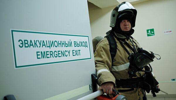 Сотрудник противопожарной службы у эвакуационного выхода во время учений в торговом центре. Архивное фото Сотрудник противопожарной службы у эвакуационного выхода во время учений в торговом центре. Архивное фото
