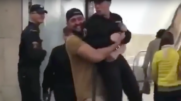 Стоп-кадр с видео, где мужчина несет сотрудника Росгвардии в руках по вестибюлю станции Сухаревская Стоп-кадр с видео, где мужчина несет сотрудника Росгвардии в руках по вестибюлю станции Сухаревская