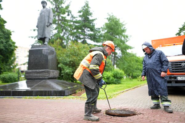 Сотрудники ГУП Мосводосток проверяют смотровой колодец Сотрудники ГУП Мосводосток проверяют смотровой колодец