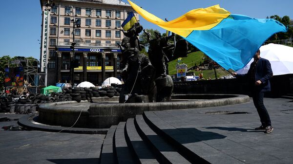 Молодой человек с украинским флагом у памятника основателям Киева на площади Независимости Молодой человек с украинским флагом у памятника основателям Киева на площади Независимости