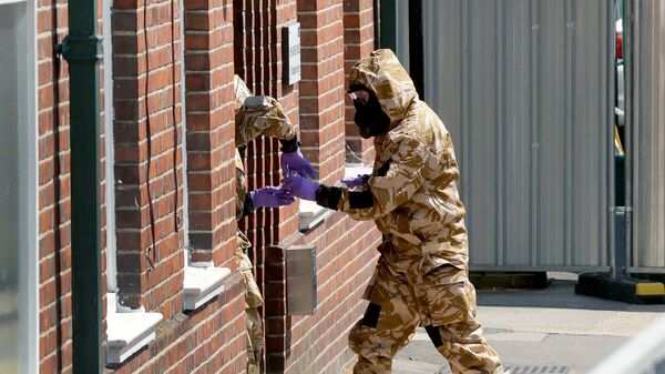 Сотрудники британских спецслужб в защитных костюмах у жилого дома в Солсбери Сотрудники британских спецслужб в защитных костюмах у жилого дома в Солсбери