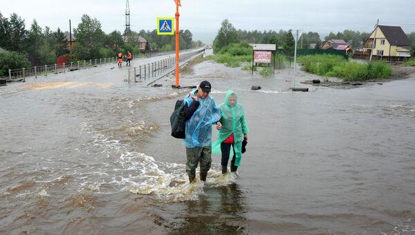 Местные жители на затопленной в результате паводка улице в Чите. Архивное фото Местные жители на затопленной в результате паводка улице в Чите. Архивное фото
