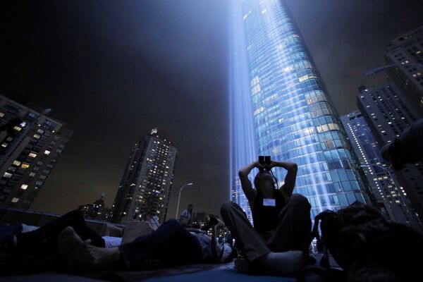 Жители Нью-Йорка наблюдают за световой инсталляцией под названием Tribute in Light Жители Нью-Йорка наблюдают за световой инсталляцией под названием Tribute in Light