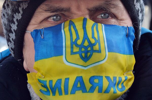 Участник акции протеста в маске с изображением флага и герба Украины в Киеве Участник акции протеста в маске с изображением флага и герба Украины в Киеве