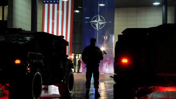 Военнослужащий сил безопасности Косово стоит перед флагами США и НАТО в Приштине Военнослужащий сил безопасности Косово стоит перед флагами США и НАТО в Приштине