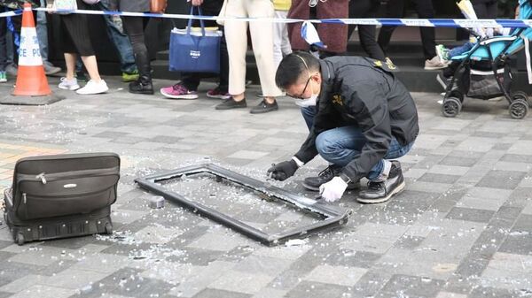 Сотрудник полиции Гонконга осматривает оконную раму, которая упала на туристку и убила ее Сотрудник полиции Гонконга осматривает оконную раму, которая упала на туристку и убила ее