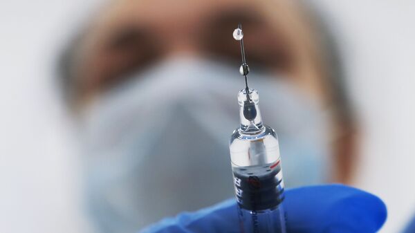 Медик готовит шприц с вакциной против гриппа