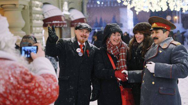 Туристы на Никольской улице в Москве фотографируются с мужчинами в костюмах В. И. Ленина и И. В. Сталина во время снегопада