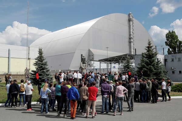 Туристы возле Нового безопасного конфайнмента над старым саркофагом, покрывающим поврежденный четвертый реактор на Чернобыльской АЭС Туристы возле Нового безопасного конфайнмента над старым саркофагом, покрывающим поврежденный четвертый реактор на Чернобыльской АЭС
