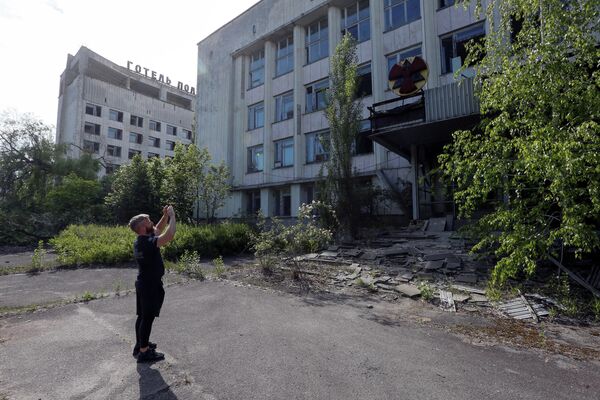 Турист фотографирует здание в заброшенном городе Припять, рядом с Чернобыльской АЭС, Украина Турист фотографирует здание в заброшенном городе Припять, рядом с Чернобыльской АЭС, Украина