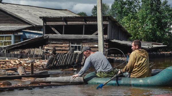 Местные жители плывут на лодке по  затопленной улице в Амурской области